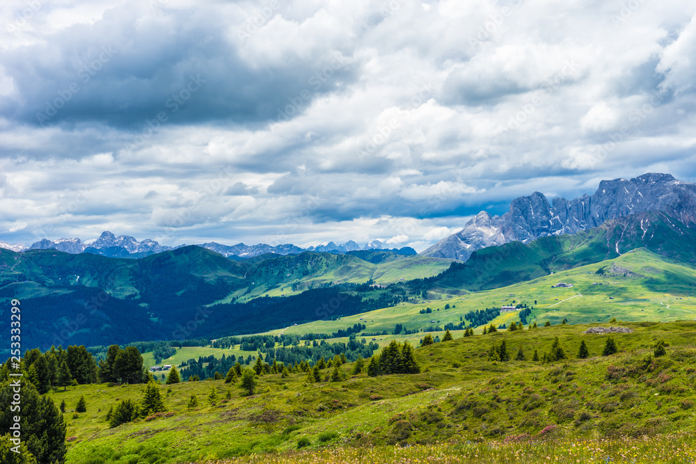 Alpe di Siusi, Seiser Alm with Sassolungo Langkofel Dolomite, a large green field with a mountain in the background Alpe di Siusi, Seiser Alm with Sassolungo Langkofel Dolomite, a large green field with a mountain in the background