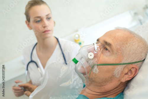 nurse observing patient wearing oxygen mask