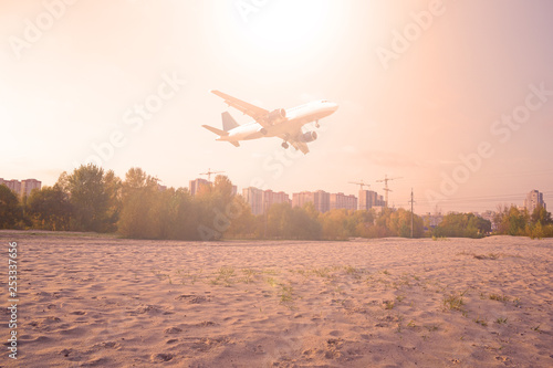 The plane over the sand and the forest the sun is shining red. photo