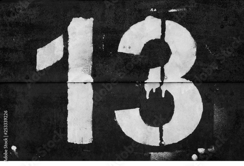 Number 13 in stencil on metal wall in black and white.