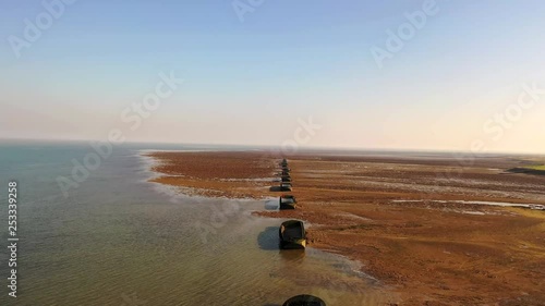 Aerial sequence featuring derelict WWII barges along the Essex coastline. Situated along the Blackwater River, part of the Dengie Peninsula and low-lying marshes near Bradwell in Essex.