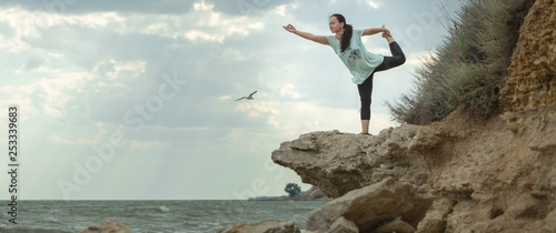 Young woman practicing yoga in nature. Ocean coast. Woman's happiness. Landscape background