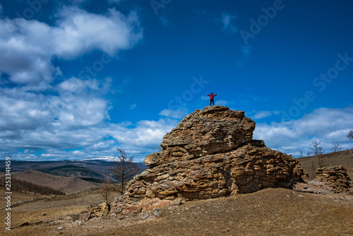 Wide steppe with yellow grass under a blue sky with white clouds and girl silhouette on top of hill, Tazheran steppe, Siberia Russia photo