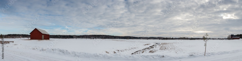 Snowy field panorama with red barn