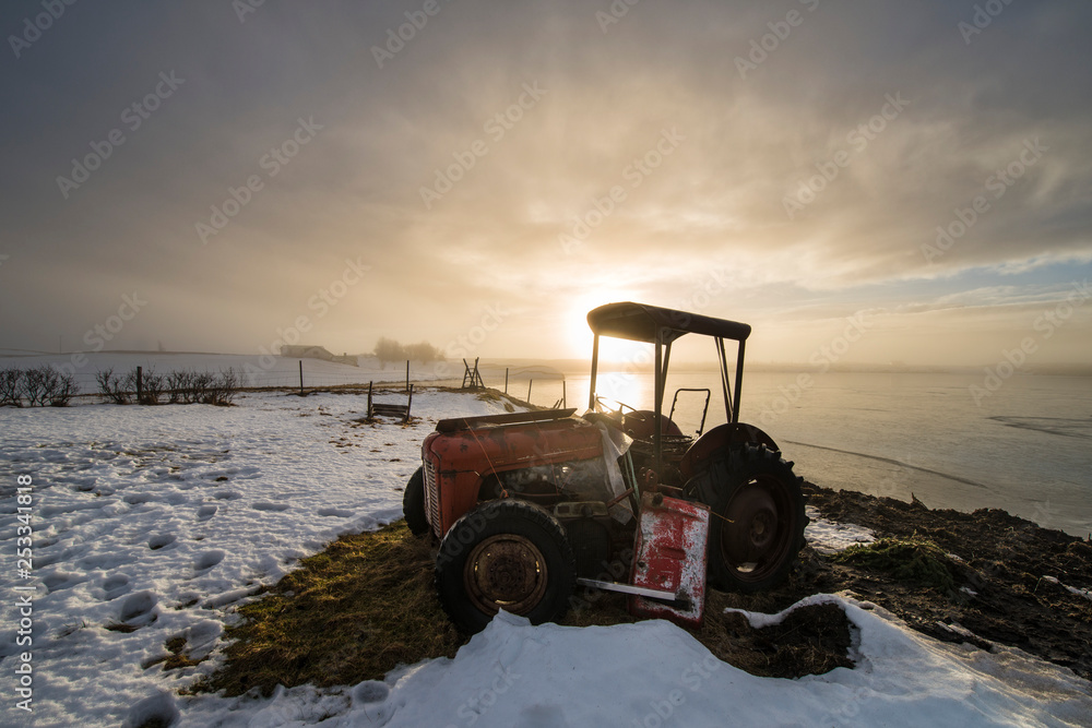 Tractor at sunrise on an icy lake Tractor at sunrise on an icy lake
