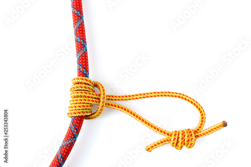Prusik Knot or Triple Sliding Hitch formed with a 5mm yellow Prusik loop around a 9.8mm red climbing rope. This friction hitch is used in climbing, canyoneering, mountaineering, caving, rope rescue.