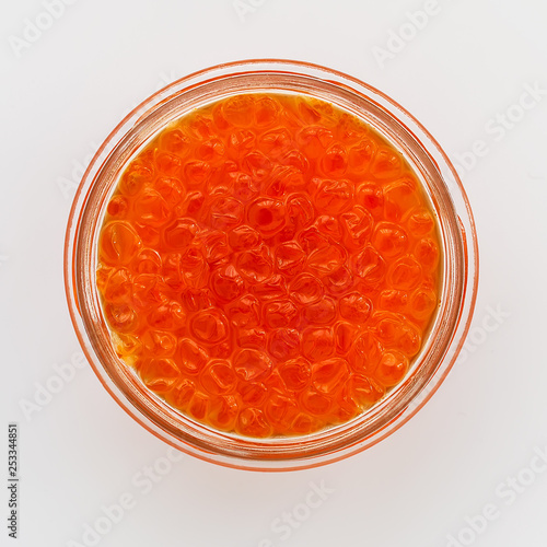 A glass jar of red caviar on a white background. Salmon caviar. Sea fish delicacy.