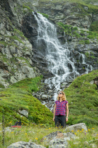 girl tourist in mountain waterfall on the background