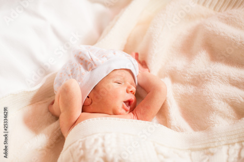 newborn is yawning, boy is lying on a white blanket. copy space for text