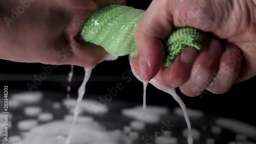 Extreme close up wring out a green rag in slow motion.