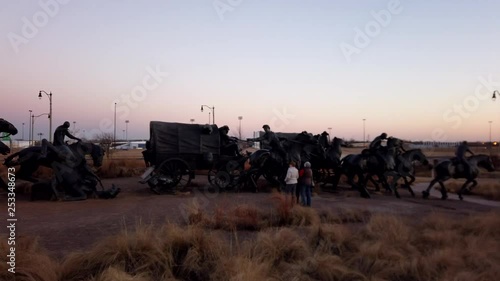 Sunset timelapse 20-second clip. Statues of a group of settlers moving through the state on horseback.  Covered wagons, horses and a hog are all represented along with the settlers themselves. photo