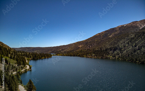 Aerial, drone view of Twin Lakes in the Eastern Sierra Nevada Mountains near Yosemite in Mono County, California with clear blue sky and water, snow capped mountain peaks, green hill sides