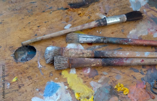 Old brushes and paints on a dirty palette in the artist's studio
