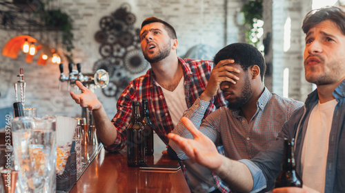 Upset friends watching football in sport bar