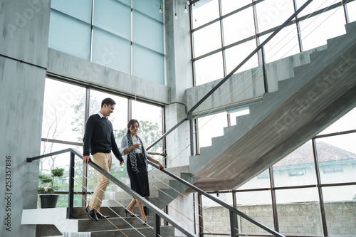 partner of business walking down with chatting on stairs in the office building