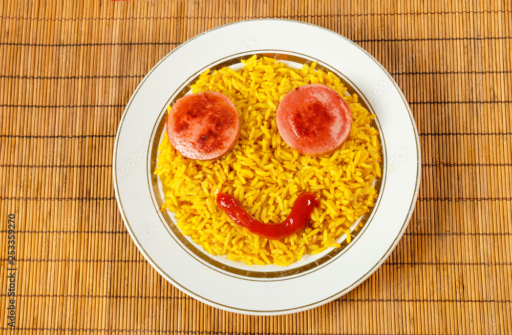 yellow rice on a plate with sausage in the form of eyes, fun food yellow rice on a plate with sausage in the form of eyes, fun food