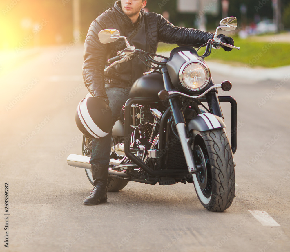 Smiling happy biker sitting on unknown big chopper bike on road Smiling happy biker sitting on unknown big chopper bike on road