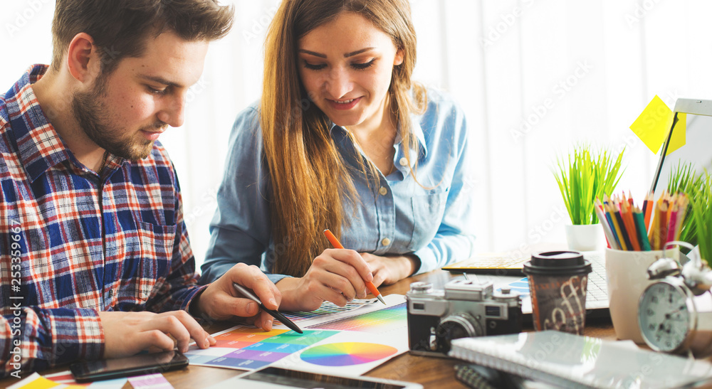 Obraz premium Two young creative designer colleagues using tablet at office