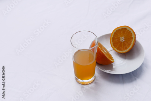 orange cut in half on a white plate on a white background and a glass of Fanta