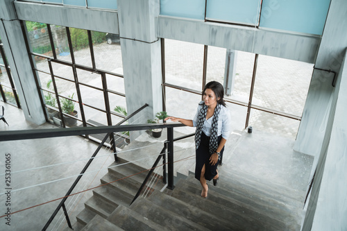 portrait of businesswoman walking up stairs alone in the office