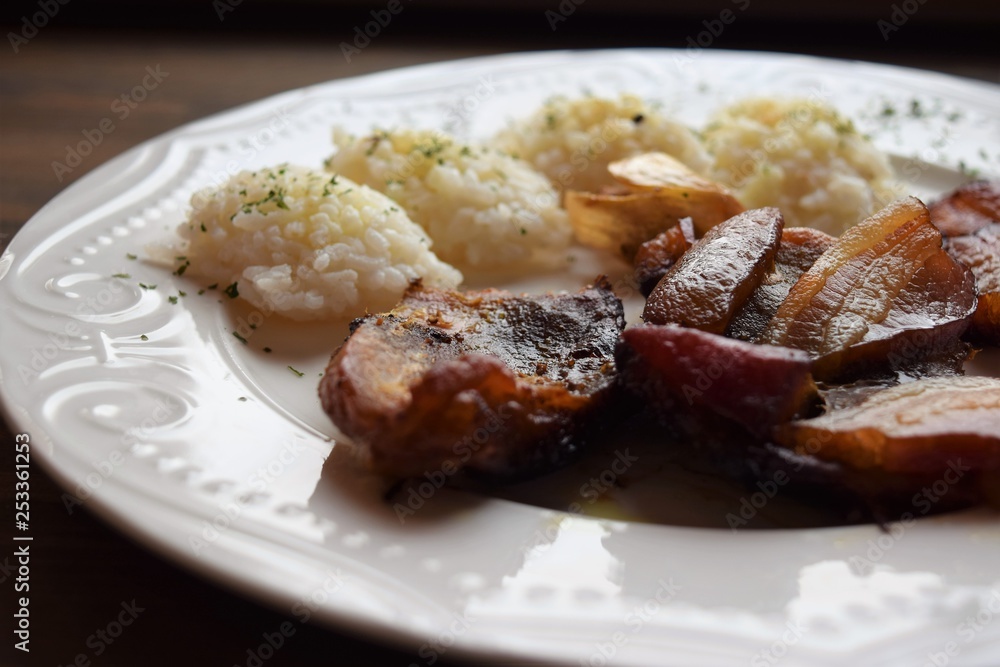 Roasted pork meat in bacon with rice on a white plate Roasted pork meat in bacon with rice on a white plate