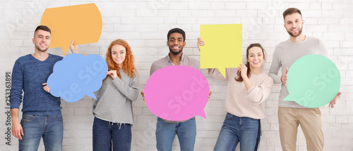 Friends holding empty speech bubbles over white wall