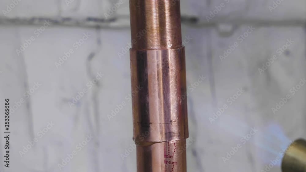 A copper pipe is welded using solder and a propane torch. Extreme closeup. A copper pipe is welded using solder and a propane torch. Extreme closeup.