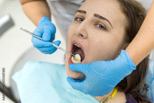 Doctor s hands with mirror checking patient s teeth