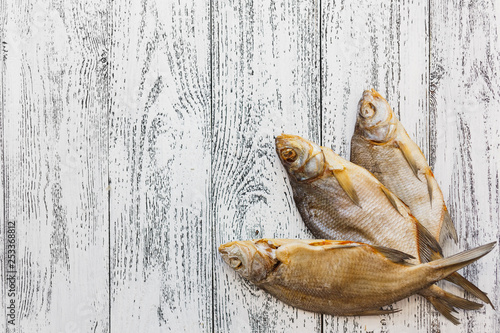 Fototapeta Naklejka Na Ścianę i Meble -  Three dried fish bream lie on a light wooden table.