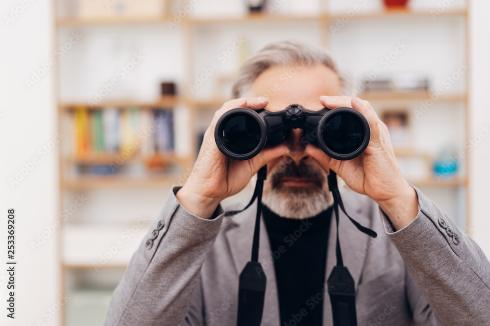 Bearded man viewing the camera through binoculars Bearded man viewing the camera through binoculars