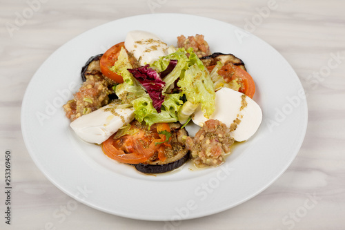 White cheese salad with tomato, eggplant and cabbage on a plate.