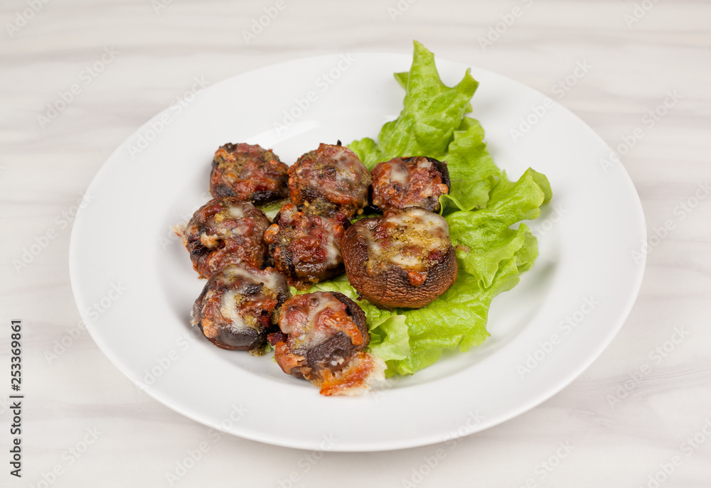 Baked champignon mushrooms stuffed with green salad on a white plate.