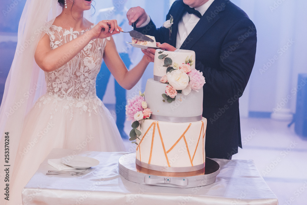 Φωτογραφία Bride and groom in love cutting beautiful three tiered modern tasty wedding cake