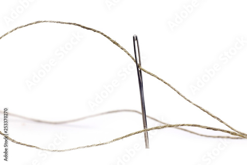 Coarse thread ball and needle on white background. Linen coarse gray threads and needle.