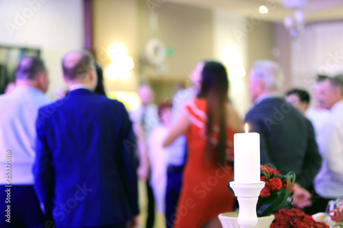 Biała świeca i ludzie w tańcu na przyjęciu weselnym.