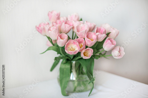 A bouquet of spring beautiful flowers in a glass vase. Fresh Pink tulips on white background.