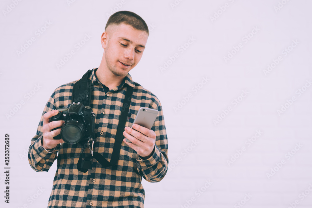 A man in a plaid shirt with a camera and a phone in search of customers A man in a plaid shirt with a camera and a phone in search of customers