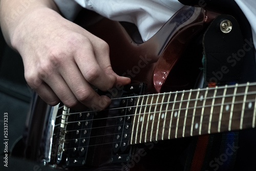 Fingers of a young guitarist on the bass strings of an electric guitar. Musical theme. Close-up.