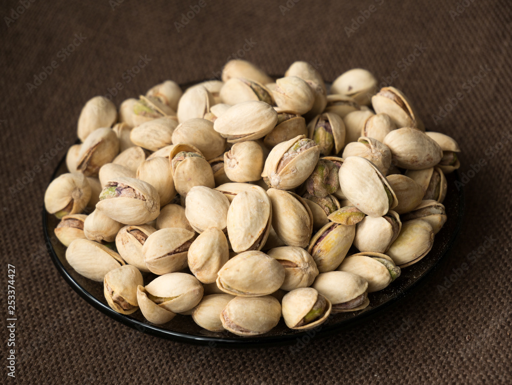 pistachio nuts in bowl on wooden background pistachio nuts in bowl on wooden background