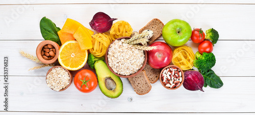 Healthy food containing carbohydrates: bread, pasta, avocados, flour, pumpkin, broccoli, beans, spinach. On a white background. Top view. Free copy space.