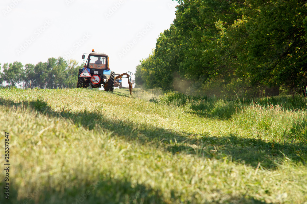 Tractors machines mowing lawn grass along road Tractors machines mowing lawn grass along road