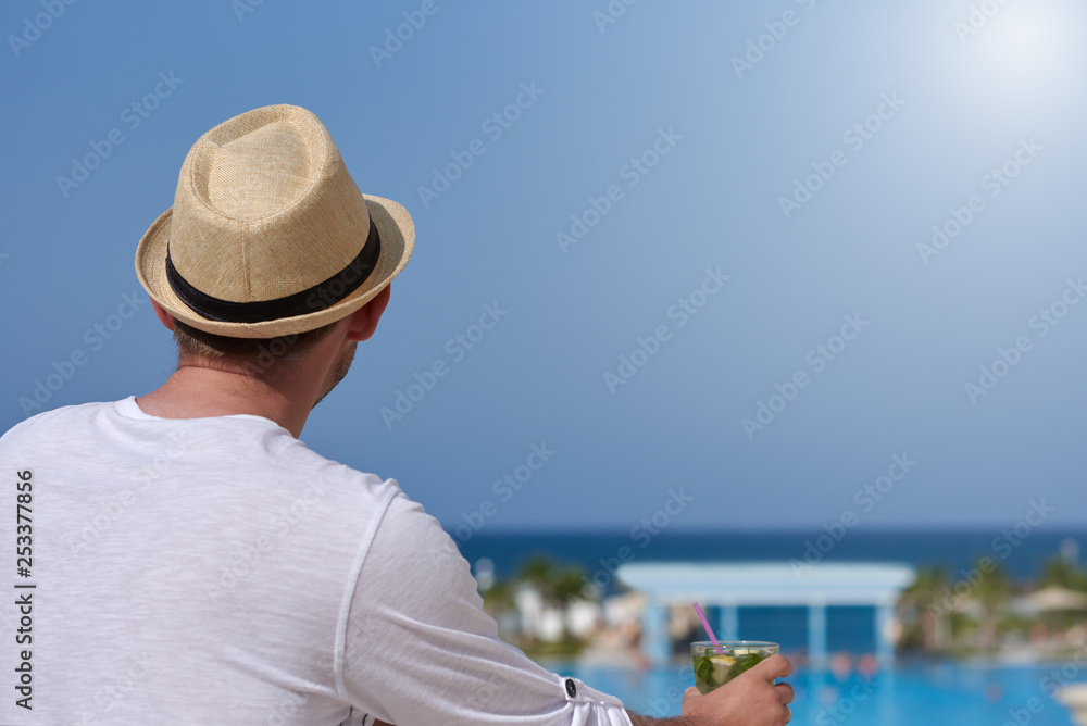 Man traveler relaxing with glass of mojito and enjoying beautiful blue sea view.