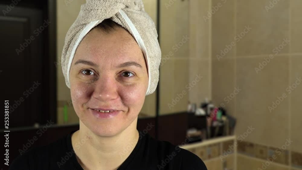 Facial skin care concept. A woman applies a clay or mud cosmetic mask on her face. Shooting on the background of tiles in the bathroom. Facial skin care concept. A woman applies a clay or mud cosmetic mask on her face. Shooting on the background of tiles in the bathroom.