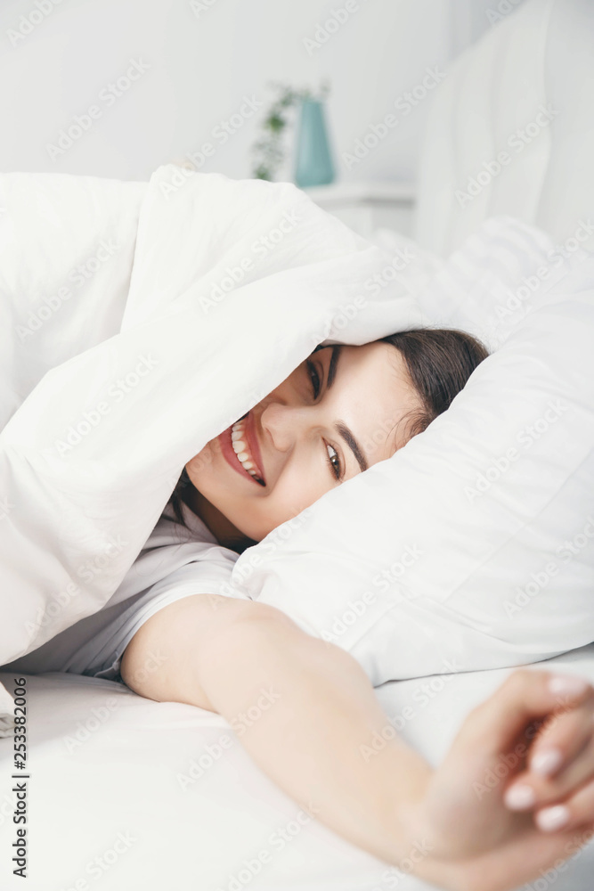 Cheerful smiling brunette woman waking up in her bed Cheerful smiling brunette woman waking up in her bed