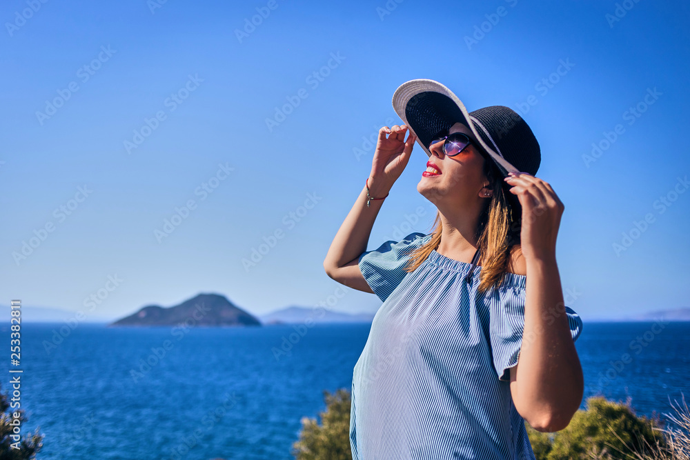 Beautiful woman in beach hat enjoying sea view with blue sky at sunny day in Bodrum, Turkey. Vacation Outdoors Seascape Summer Travel Concept Beautiful woman in beach hat enjoying sea view with blue sky at sunny day in Bodrum, Turkey. Vacation Outdoors Seascape Summer Travel Concept