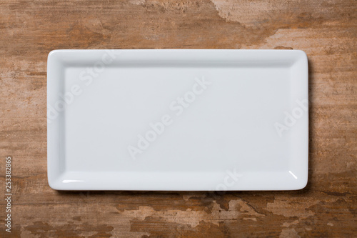 Empty white plate on brown wooden background