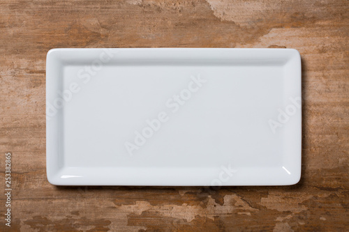 Empty white plate on brown wooden background photo