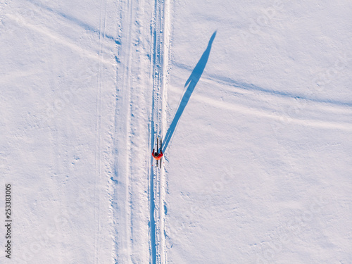 Woman on cross-country skiing rides on snowy track. Leisure concept. Aerial top view