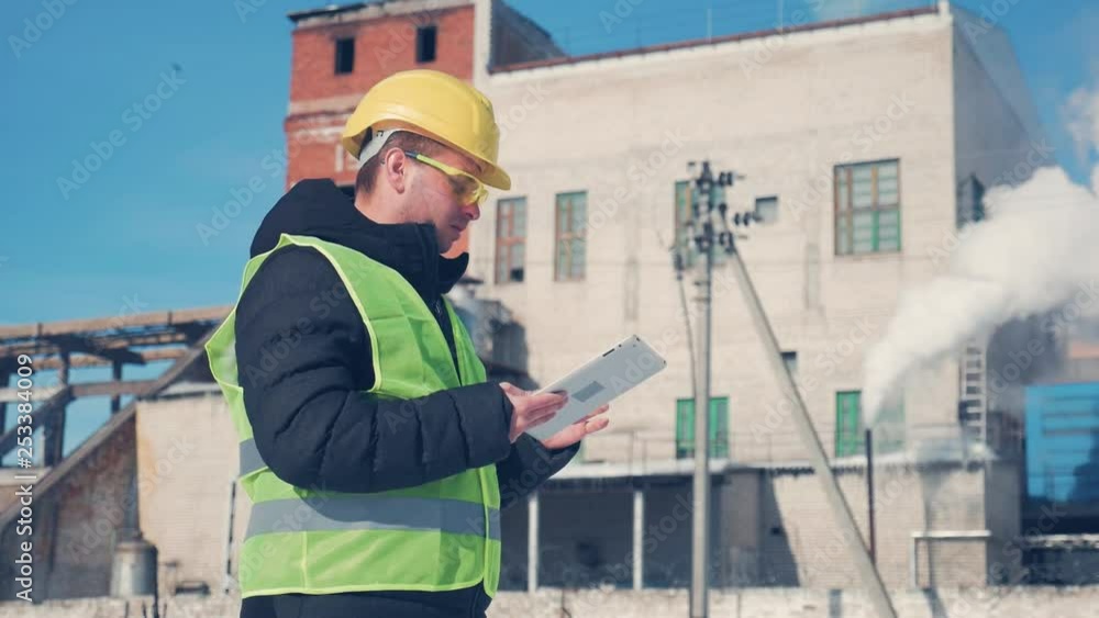 Engineer in hard hat is using a tablet computer in a industry factory. Engineer in hard hat is using a tablet computer in a industry factory.