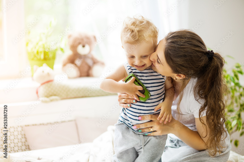 Young mother kissing her baby lying on the bed Young mother kissing her baby lying on the bed